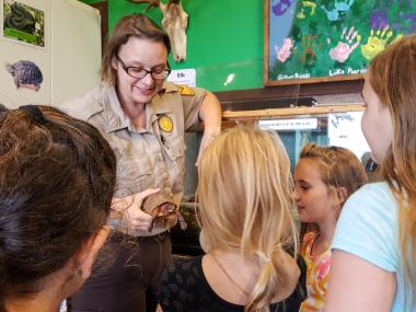 A group of children looking at a turtle held by an Arkansas State Park interpreter during a indoor workshop
