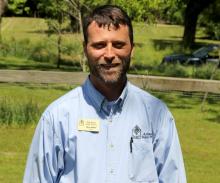 Picture of Chris Adams outside at Historic Washington State Park. He's wearing a blue shirt, smiling, has brown hair and a beard. There is a green grass in the background.