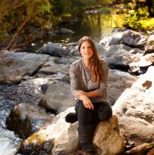 Zoie Clift sitting outside alongside a stream
