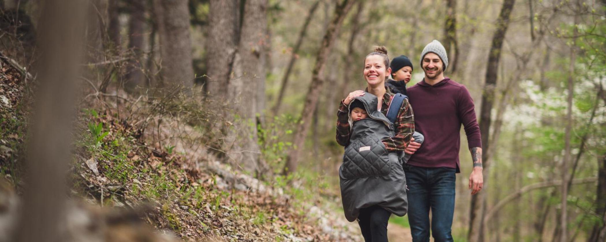 Family hiking at Hobbs State Park-Conservation Area in the fall. Mom has baby in front carrying backpack and the dad is carrying another small child.