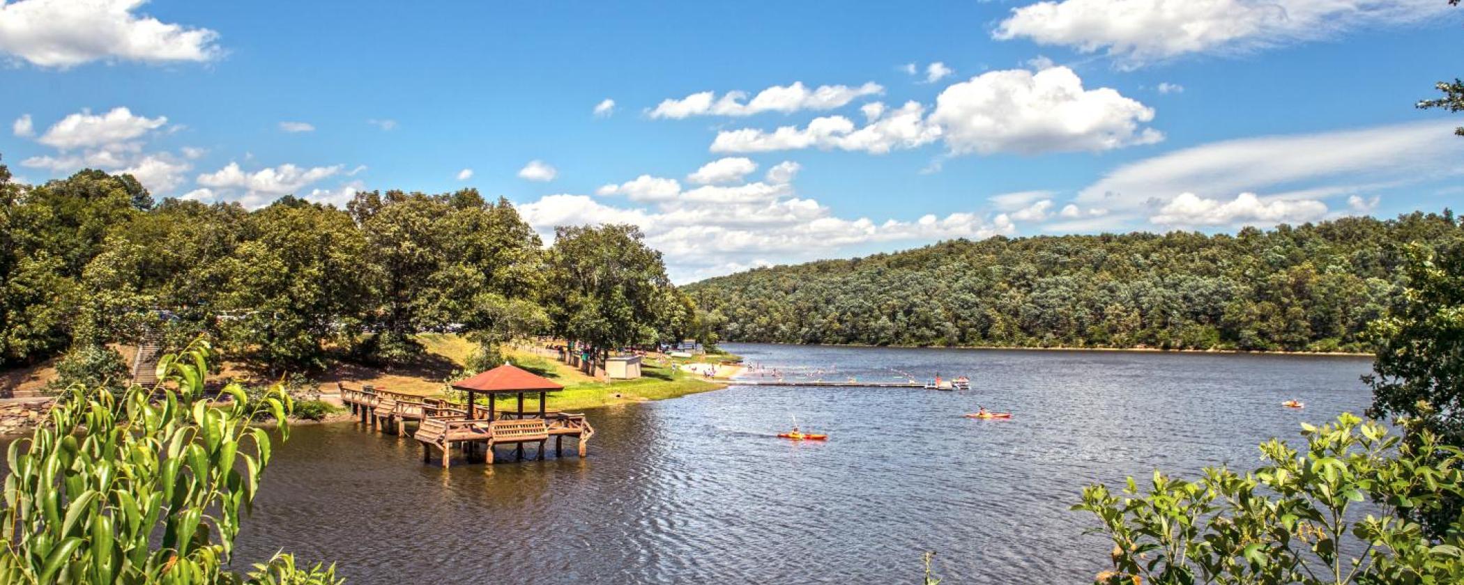 40-acre Lake Bennett surrounded by trees and greenery with a covered dock at Woolly Hollow State Park