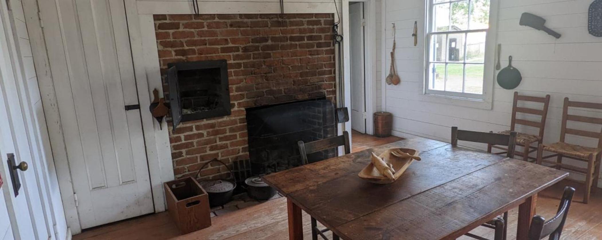 Front room of Sanders kitchen at Historic Washington State Park. There is a table and coal fireplace