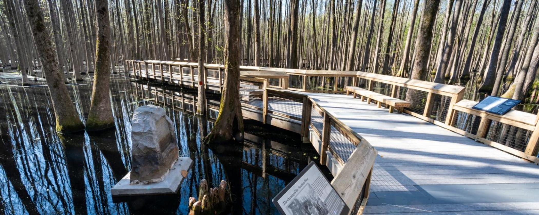 An elevated boardwalk leads to a granite monument at Louisiana Purchase State Park. Arkansas Tourism file photo.