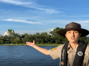 Park interpreter Jenn Menge motioning to purple martins on Lake Ouachita