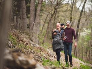 Family hiking at Hobbs State Park-Conservation Area in the fall. Mom has baby in front carrying backpack and the dad is carrying another small child.