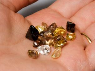 Someone holding white yellow and brown diamonds found at Crater of Diamonds State Park in their hand