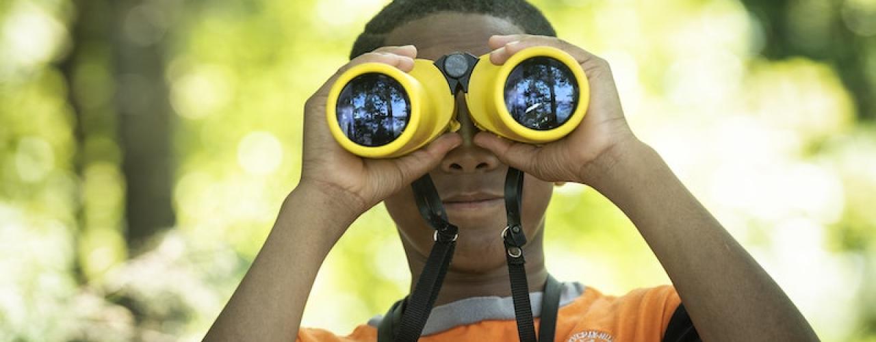 A young looking through a pair of binoculars