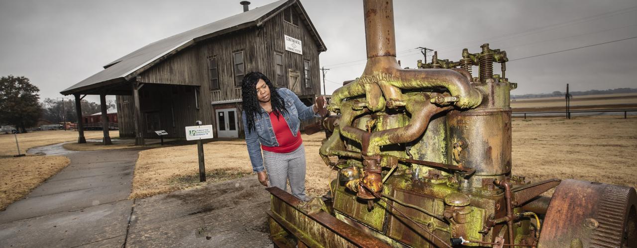 A woman looking at a piece of historic agricultural equipment at the Plantation Agriculture Museum