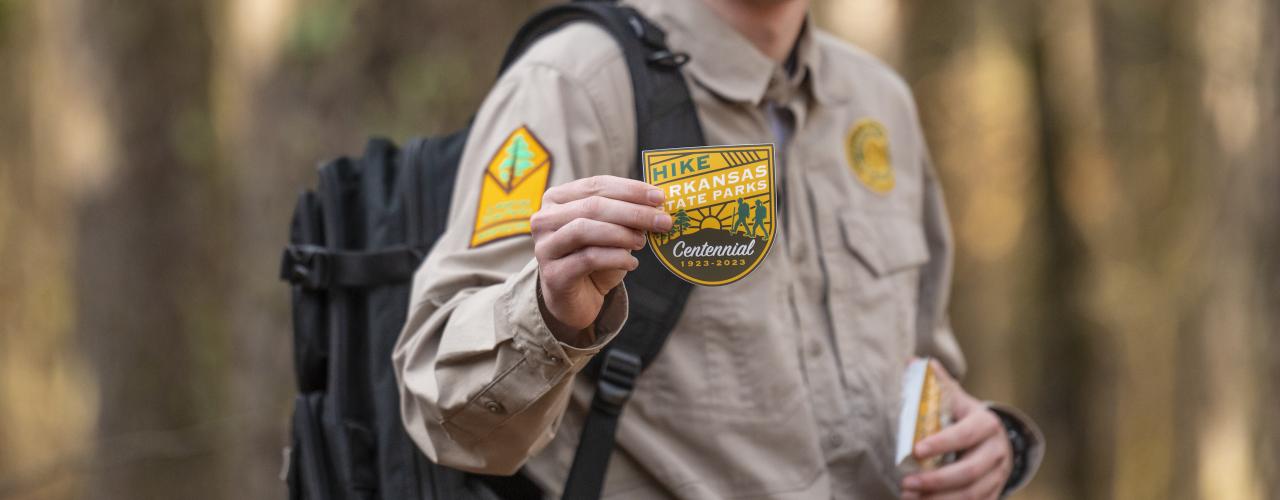 Park Interpreter holds up a sticker for first day hikes
