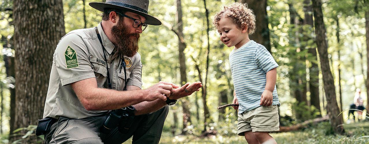 Park ranger and kid looking at rocks at the park