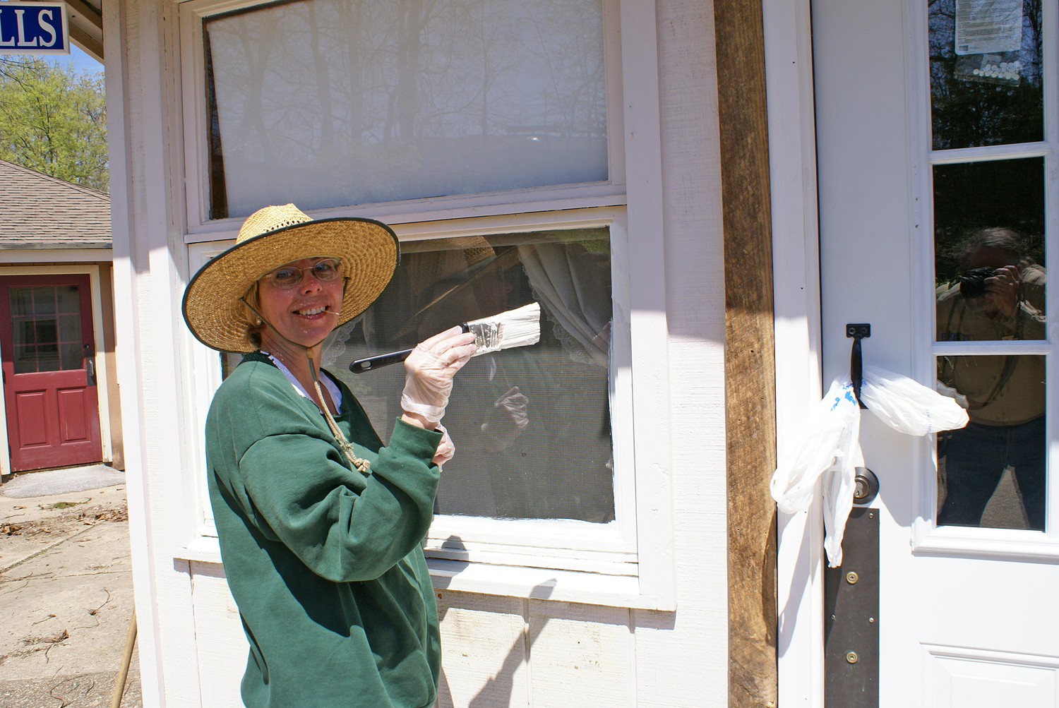 Volunteer and jeweler Linda Widmer paints the trim on the Doll Shop windows.